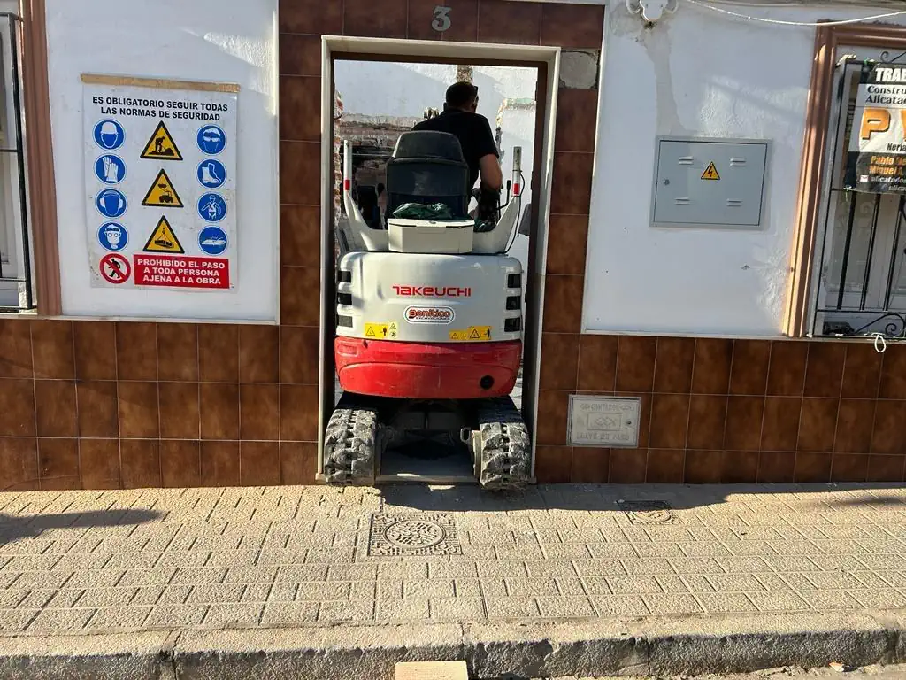 Mini retroexcavadora en callejón andaluz